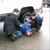 Photo courtesy of YouTube.  RCMP officers watch over 51-year-old, Buddy Tavaras after he was kicked in the face. 