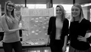 Students Andrea Janish, Alex Blackwell and Bridgette Slater stand beside their creation: a poster asking MRU, “What makes you feel fearless?” For answering, students receive a box of matches held together with a bobby pin | Photo by Nina Grossman 